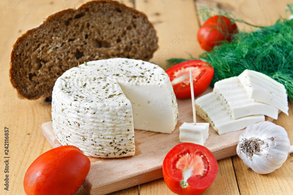 White cheese, bread, tomatoes and garlic on a wooden background White cheese, bread, tomatoes and garlic on a wooden background