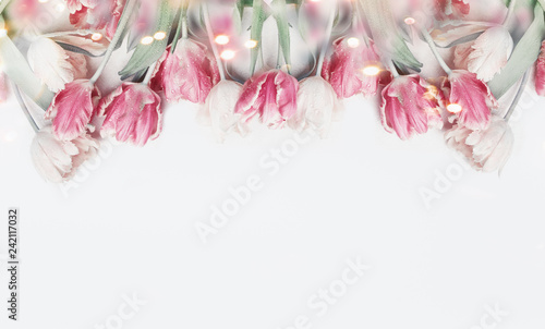 Lovely pastel color tulips border on white background with bokeh. Springtime flowers, top view. Spring nature and holidays concept. Copy space for your design. Layout for greeting card photo