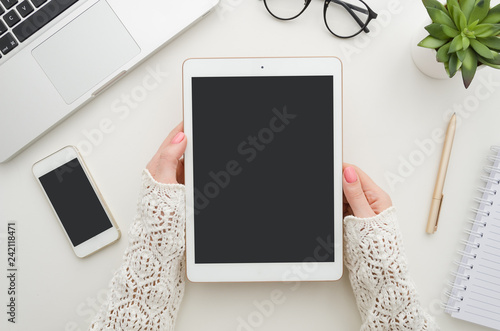 Cropped shot top view of businesswoman hands using tablet and smartphone mockup at the white office desk. Blank screen mobile phone for graphic display montage