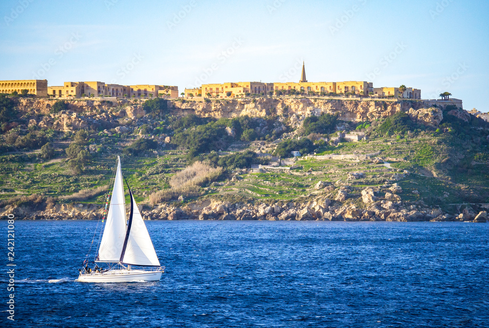 View of Gozo island in Malta with blue sea and a white sailboat