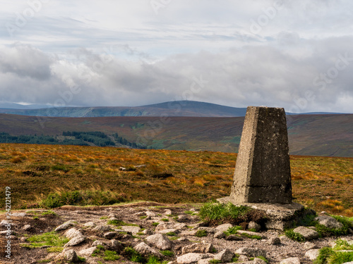 Two Rock Mountain summit on a cloudy summer day in Dublin Mountains, Ireland. Landscape of an Irish mountain peak with a triangulation pillar in the foreground.