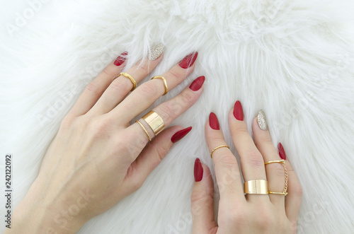 Картината върху платно Woman hands with red nail art and jewelry on fur background.
