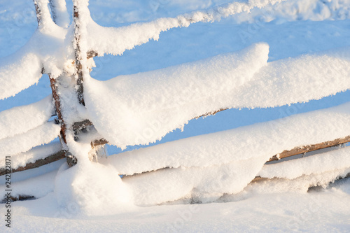 Old wooden fence covered with snow. Winter landscape in Finland. photo