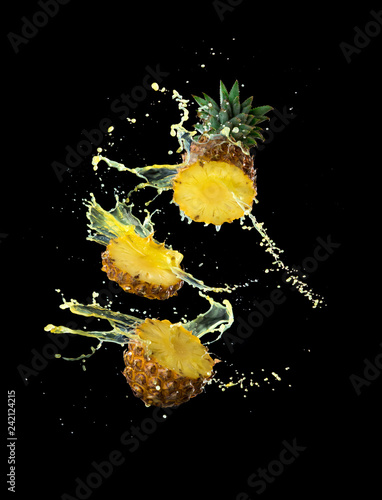 Slice of yellow pineapple with splashing pineapple juice isolated on black background