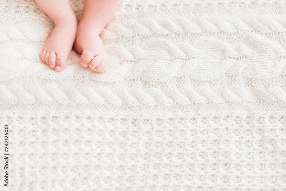 Baby's feet on white knitted background. Little child's bare feet. Cozy morning bedtime at home. Place for text. Baby's feet on white knitted background. Little child's bare feet. Cozy morning bedtime at home. Place for text.