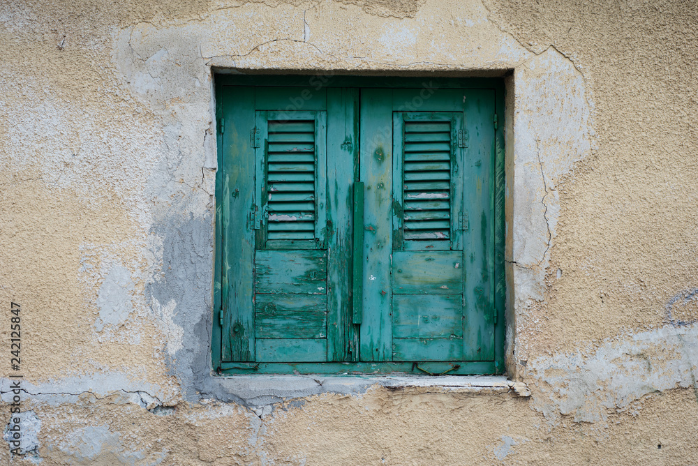 Window with turquoise shutters and blinds on the background wall of the yellow sandstone. Window with turquoise shutters and blinds on the background wall of the yellow sandstone.