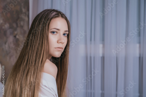 portrait of young cute girl with long hair in bedroom copy-space