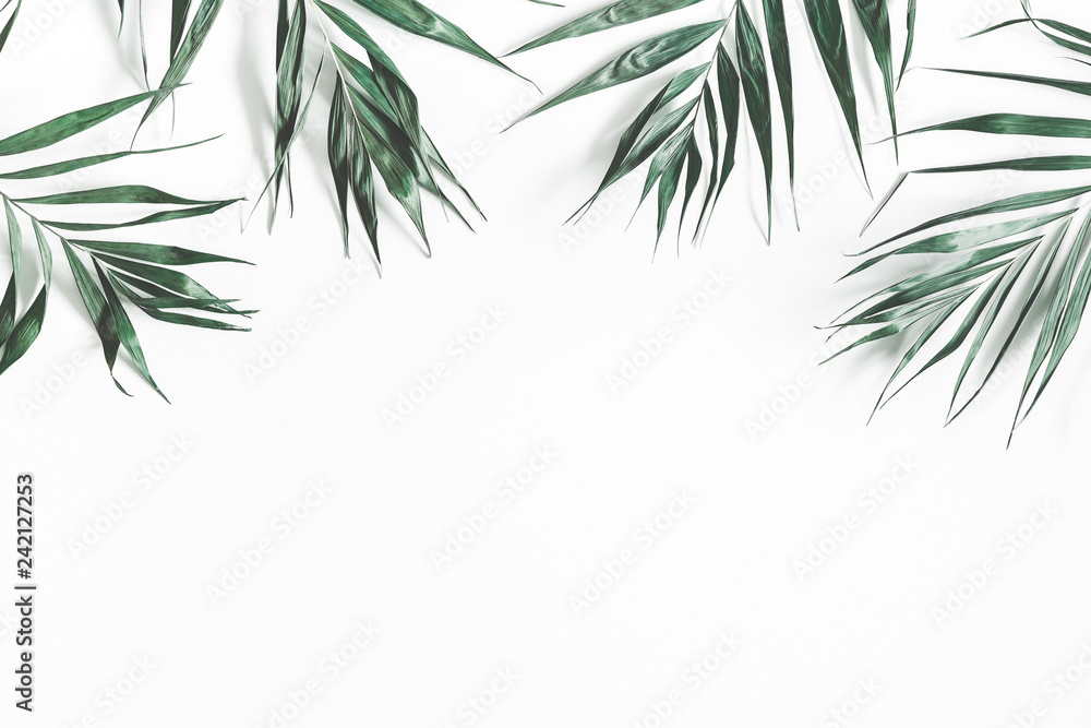 Green palm leaves on white background. Flat lay, top view, copy space
