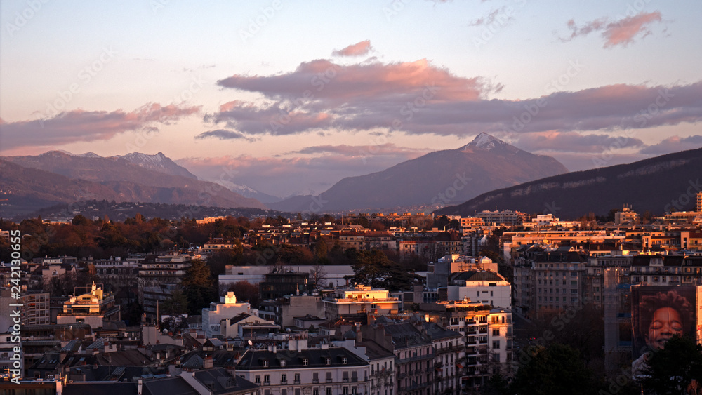 Panoramic cityscapes of Geneva in Switzerland.  The images show the rooftops of Geneva and the surrounding mountains at sunset as the sunlight reflects off the roofs and windows of the buildings.