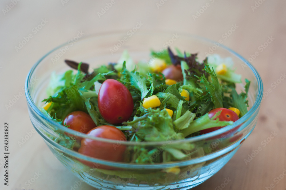 A fresh and healthy salad made with fruits and vegetables on a wooden table.