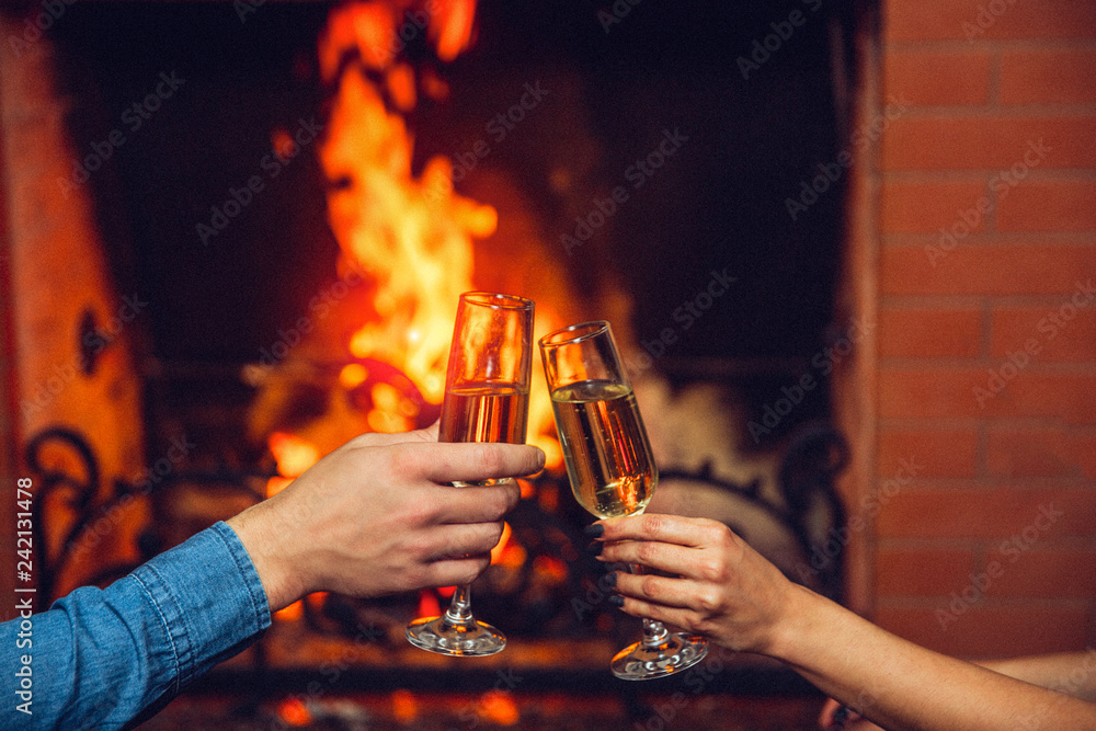 © estradaanton - Cut view of man and woman hands holding glasses with champaigne. They touch it in front of fireplace. © estradaanton - Cut view of man and woman hands holding glasses with champaigne. They touch it in front of fireplace.