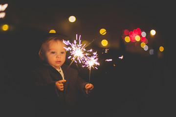 Waist up portrait of happy family celebrating New Year together and lighting sparklers outdoors