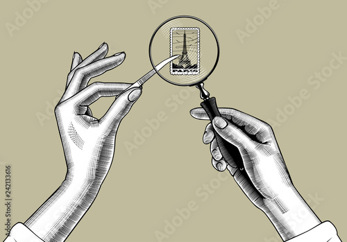 Female hands with holding magnifying glass and postage stamp with the Eiffel Tower