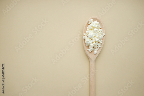 Cottage cheese in a wooden spoon, top view with copy space photo