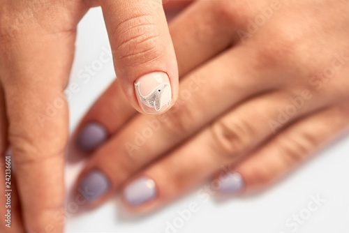 Close-up of professional manicurist hands painted elegant abstract silver glitter design on client woman painted nails in beauty salon. Beauty and fashion concept. photo
