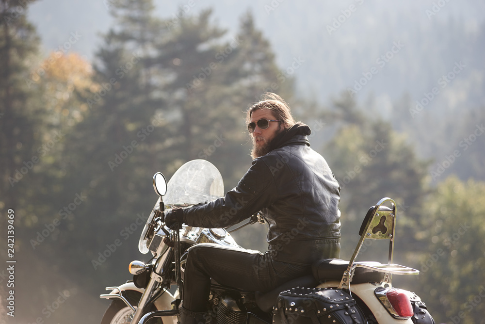 Back view of bearded biker with long hair in black leather jacket
