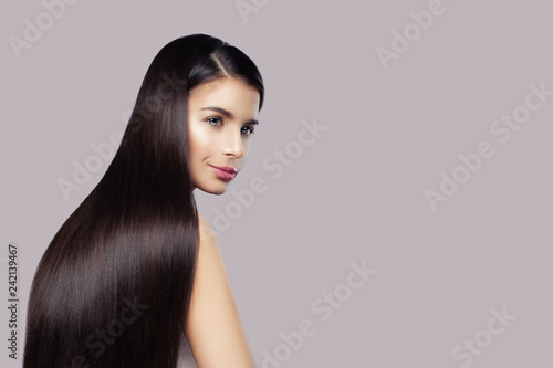 Fashion beauty portrait of cute brunette woman with long healthy hair on pink background