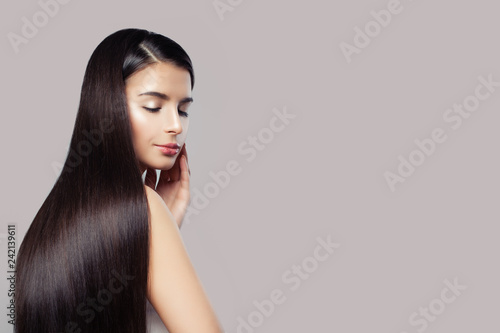 Attractive woman with long healthy straight hair on pink background