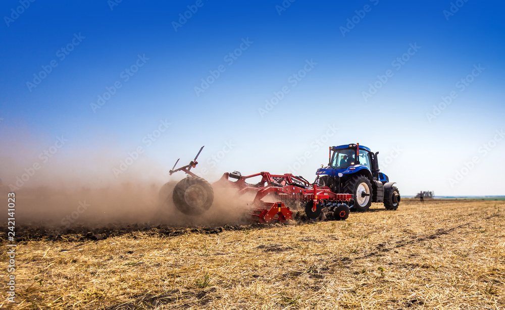 Obraz premium The tractor plows the field, cultivates the soil for sowing grain. The concept of agriculture.