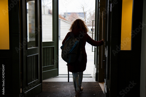 Young curly girl leaves the room through open doors 

