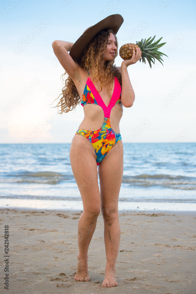 Naklejka premium Beautiful woman holding pineapple and having fun on the beach