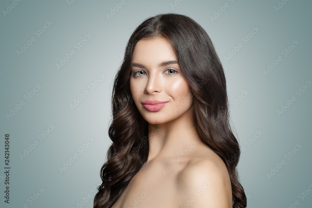 Healthy woman with clear skin and wavy hair smiling on blue background Healthy woman with clear skin and wavy hair smiling on blue background