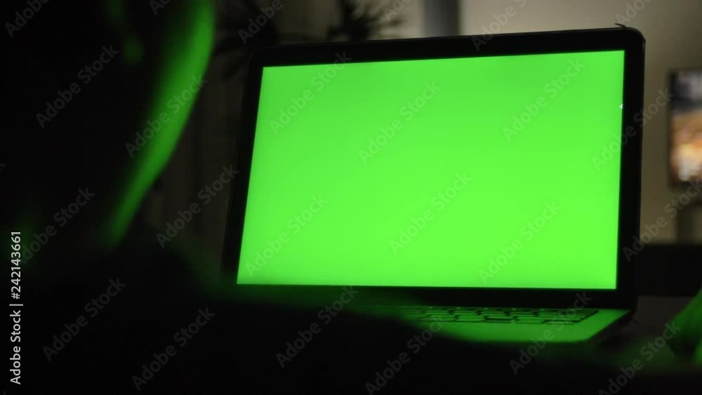 Over the shoulder view of typing and watching on computer . Green screen of technology being used. Chroma Key laptop. Over the shoulder view of typing and watching on computer . Green screen of technology being used. Chroma Key laptop.