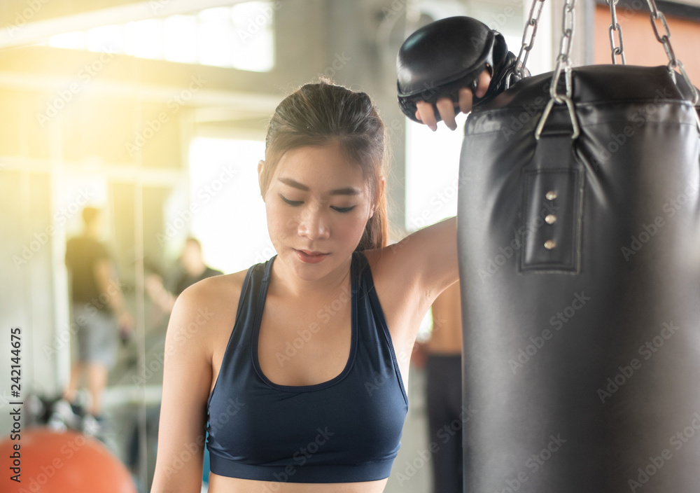 Attractive female boxer training with kick boxing at gym with blackgloves.