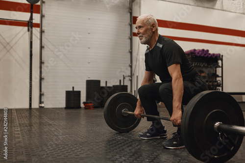 Fotografie Athletic unshaven grandfather wearing stylish sports clohtes and sneakers posing