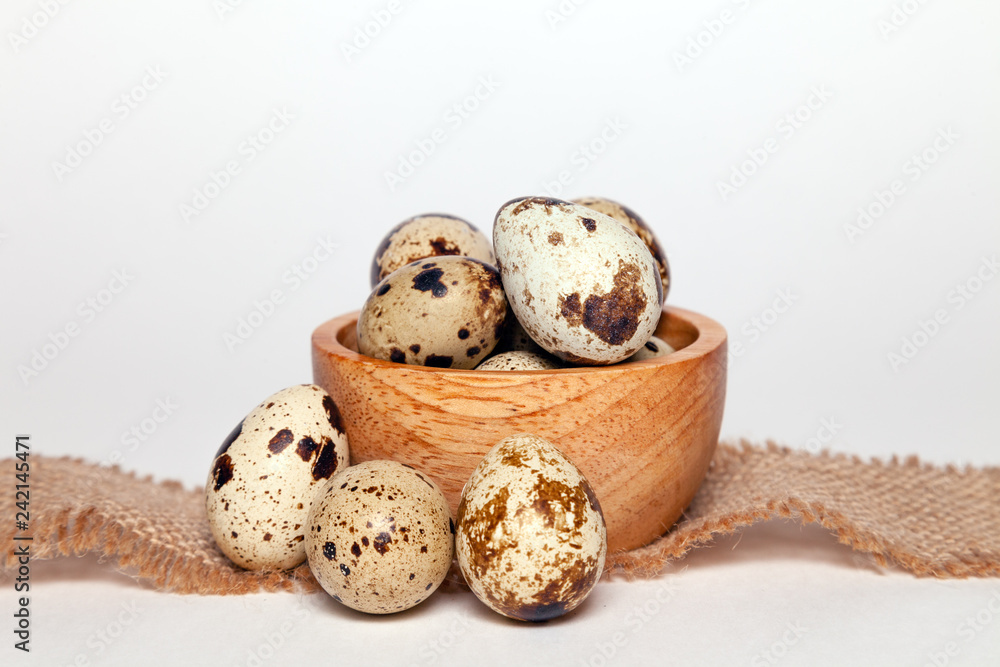 Closeup Easter small fresh textural quail eggs in round wooden bowl with textile isolated on white background. Concept traditional treat Orthodox Christian spring Church holiday. Free space, copyspace Closeup Easter small fresh textural quail eggs in round wooden bowl with textile isolated on white background. Concept traditional treat Orthodox Christian spring Church holiday. Free space, copyspace