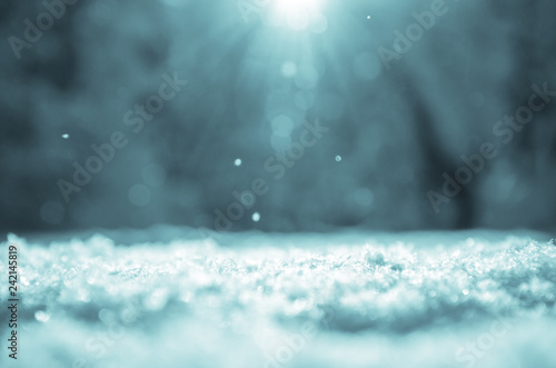 Sunny winter christmas background with snowdrift on a foreground and blurred forest landscape on a background.
