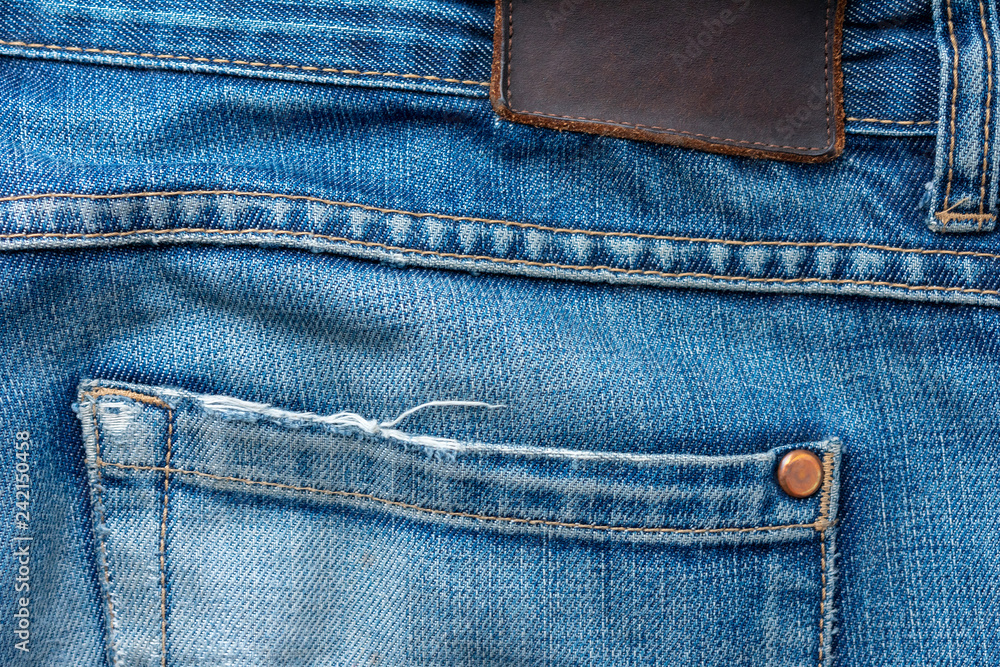 Back of old blue jeans with pocket and a leather tag. Close-up photo. Back of old blue jeans with pocket and a leather tag. Close-up photo.