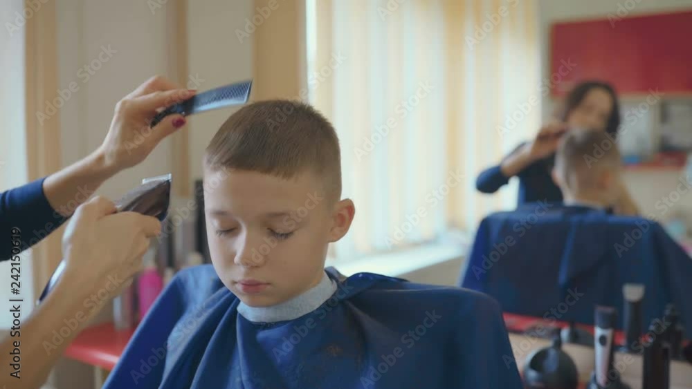 Hairdresser cutting hair with barber scissors in children hairdressing salon. Hairdresser cutting hair with barber scissors in children hairdressing salon.