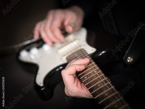 Male hands playing on electric guitar, close up, selected focus