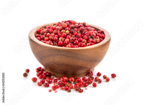 dried pink peppers in wood bowl isolated on white background