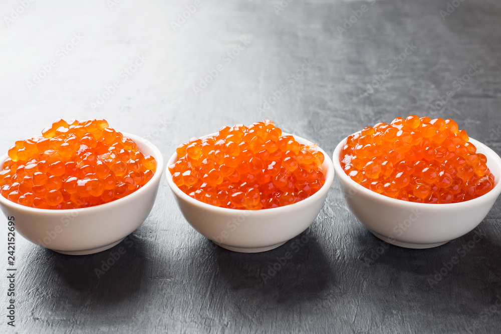 red salmon caviar in a plate on a dark table. red salmon caviar in a plate on a dark table.