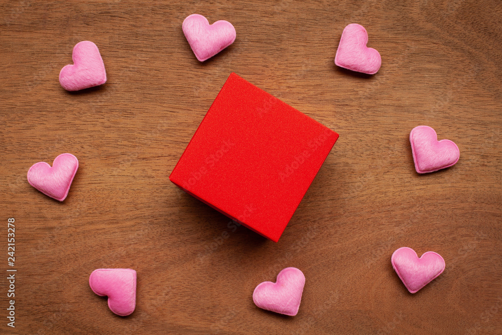 Obraz premium Red gift box with pink hearts on wooden table. Valentine day present background. Top view and copy space