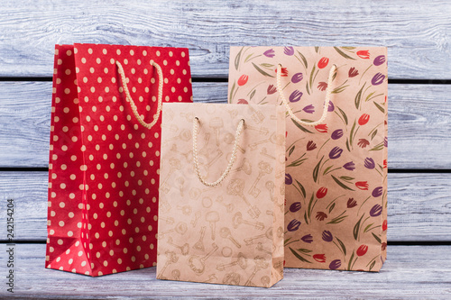 Set of shopping bags on wooden background. Three colorful gift bags. Business, retail, sale and commerce concept.