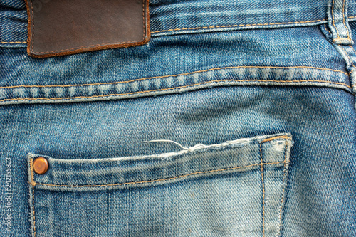 Back of old blue jeans with pocket and a leather tag. Close-up photo.