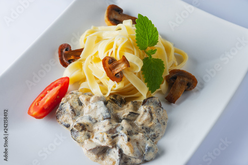 Pasta Fetuccine with creamy alfredo mushroom sauce on a white plate.Creen leaf. Close up. Selective focus. photo