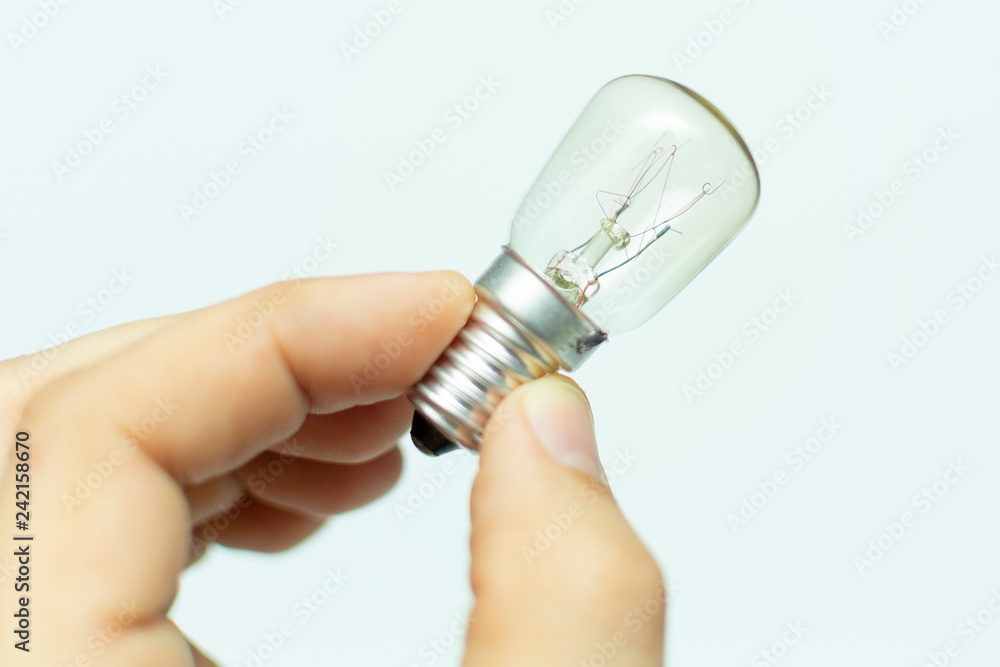 a small light bulb with a tungsten filament in hand, close-up a small light bulb with a tungsten filament in hand, close-up