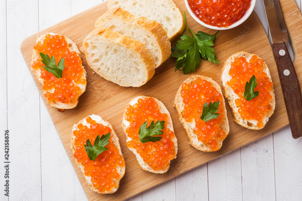 Sandwiches with red salmon caviar on a wooden Board. White table top. Sandwiches with red salmon caviar on a wooden Board. White table top.