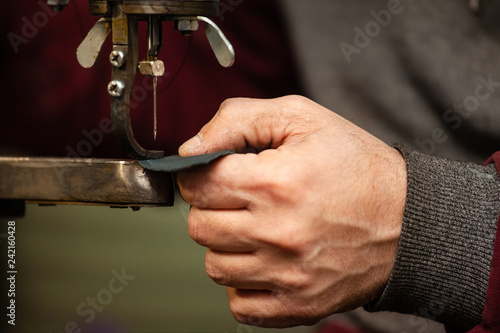 close-up of a shoemaker's hand stitching a shoe detail