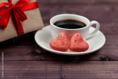 Two hearts, coffee and a gift for Valentine's Day on a wooden background