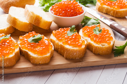 Sandwiches with red salmon caviar on a wooden Board. White table top.