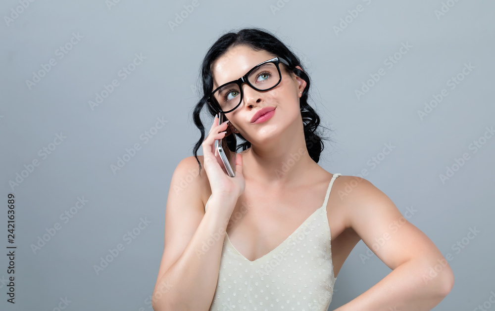 Young woman talking her the cellphone on a gray background Young woman talking her the cellphone on a gray background