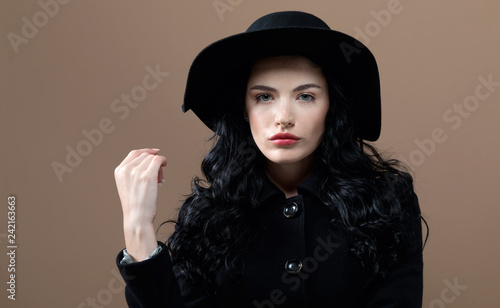 Beautiful young woman in a fashionable coat on a brown background © Tierney