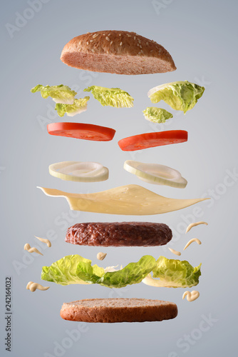Classic beef burger with onion floating on gray background