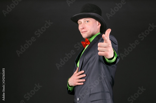 Принти на полотні Man in a bowler hat is winking and is pointing by his index finger ahead on black background
