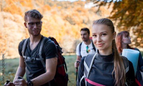 Smiling young hiker woman with backpack trekking in the company of friends © leszekglasner